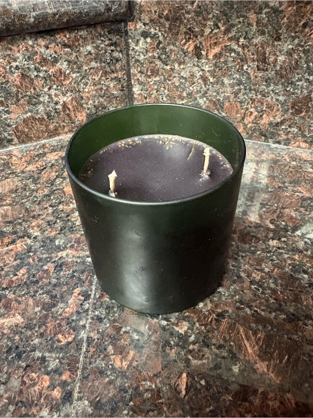 Handmade candle black licorice scented wax poured into a dark green vessel